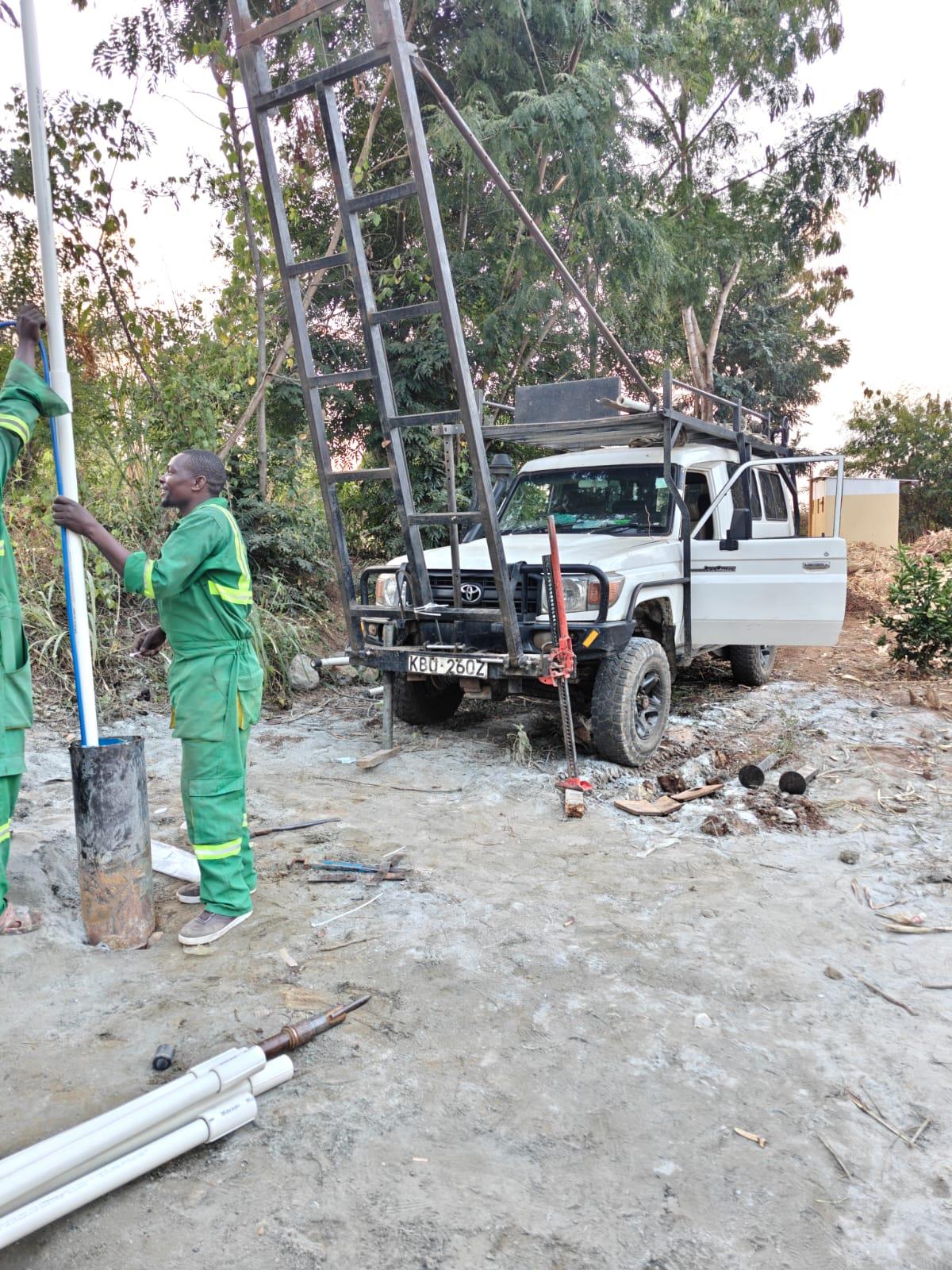 Borehole drilling in Kenya — Amroth crew lowering casing pipe into a newly drilled borehole